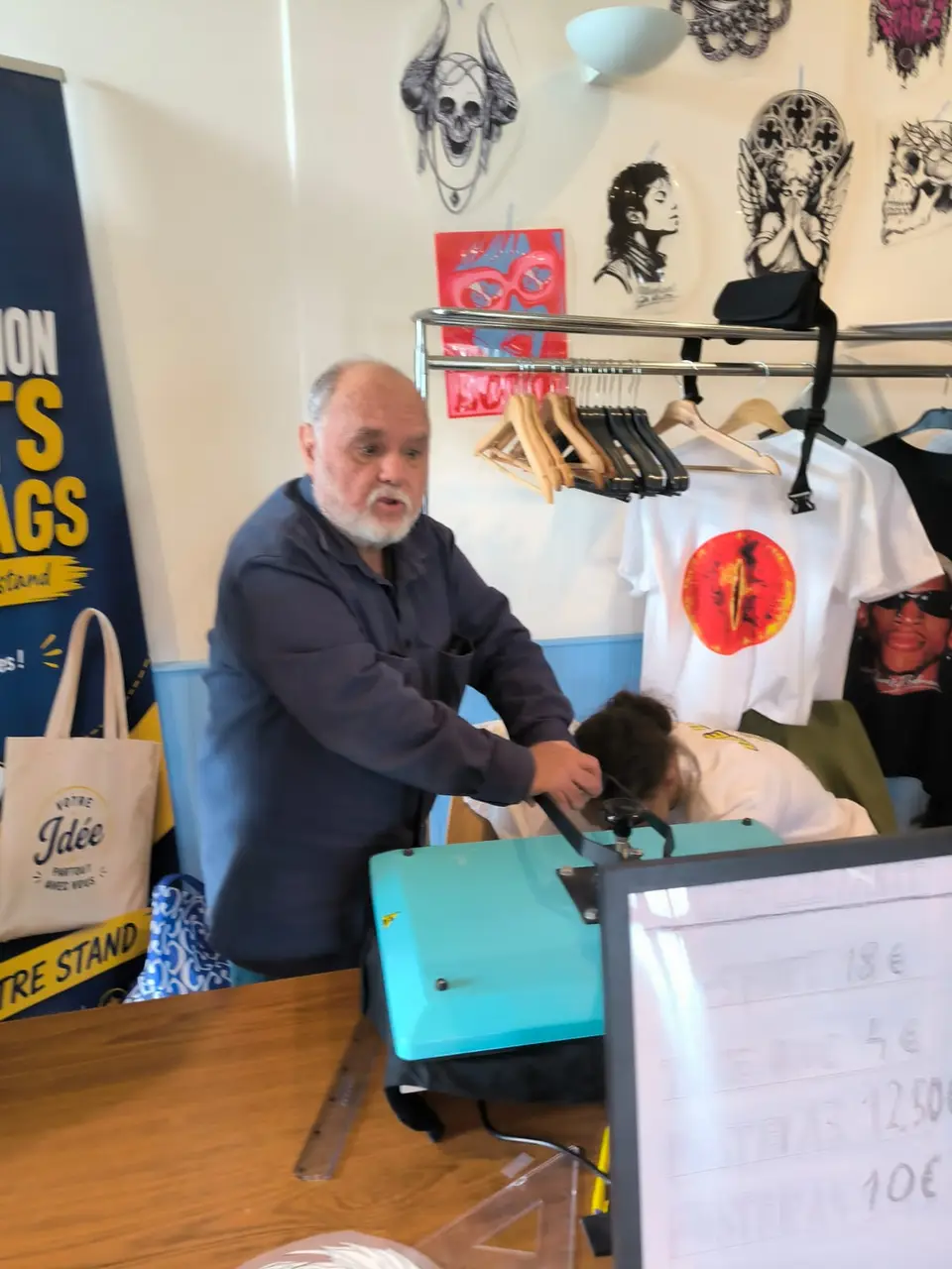 Un visiteur regarde le vêtement passer sous la presse à chaud, sur le stand de l'association.